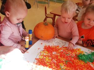 Dzieci wyklejają bibułą dynię grupa 1